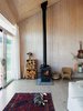 Modern home with Living Room, Light Hardwood Floor, Chair, Standard Layout Fireplace, and Wood Burning Fireplace. The restrained 820-square-foot interior is defined by the angular ceiling. Garlick left the prefabricated structural panels unfinished to save on material costs. A True North wood stove from Pacific Energy heats the house. Max, the family’s cat, naps on a vintage rug purchased on eBay. Photo 3 of Sky House
