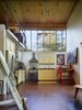 The kitchen and living area occupies the ground level of the double-height interior while a sleeping loft is above. Photo 7 of Scavenger Studio modern home