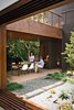 Modern home with Outdoor, Back Yard, Trees, Shrubs, Hardscapes, Small Patio, Porch, Deck, Raised Planters, Tile Patio, Porch, Deck, and Landscape Lighting. The couple often dine on the patio off the kitchen, warmed by a fireplace from Spark Modern Fires. Photo by Coral von Zumwalt. Photo of Eames Molded Chairs