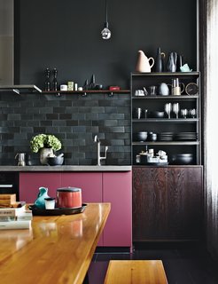 No whiteware here. In this moody apartment in Berlin, multi-toned charcoal gray subway tiles make up the backsplash, which contrasts with the pop of rosy color on the kitchen cabinets. 