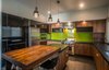 A green backsplash adds a dash of color while the kitchen island sits under a series of pendant lights. The kitchen features Electrolux and Wolf appliances. Photo 4 of A Home Rocks Out with Natural Stone, Concrete, and a Volcano modern home