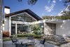 The entry courtyard provides a natural extension to the living room. Tiled in silver-speckled sandstone, its stacked steps echo the home’s minimalist, rectilinear design. The patio’s only furniture is a set of vintage lounge chairs. “These were chosen for their diaphanous appearance, because we didn't want anything obstructing the beautiful exterior views,” interior designer Joshua Rice says. Photo 2 of Preston Hollow modern home