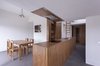 With limited space, Heierle maximized the living area with a multi-functional kitchen island. The side facing the living room acts like a bar; a sink and countertop extend the kitchen area; and the counter across from the entryway often holds key or packages when the client arrives home. "It's a miniature of the entire apartment," Heierle says of the centerpiece, "one object having multiple uses." The island, along with all the oak furniture and custom casework in the apartment, was all built and designed by a friend of the owner who lives in the same rural Romanian village where he grew up. Photo of Minimal Romanian Attic Renovation Complete with an Epic Bathtub modern home