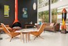 Modern home with Living Room, Wood Burning Fireplace, Chair, Sofa, Pendant Lighting, and End Tables. In the living room of a remodel in Seattle, the fireplace was powder-coated orange to complement the vintage furnishings. The sofa is from Design Within Reach; the coffee table is by Alexander Girard for Knoll. A pair of undated paintings by Arthur L. Kaye hang on a wall painted in a Benjamin Moore hue custom matched to the outside of the window frames. The triangular nesting tables are a vintage find. “They’re always billed as ‘guitar pick tables,’” resident Sally Julien says. Photo of How to Design with Orange