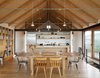 Modern home with Dining Room, Storage, Chair, Light Hardwood Floor, Pendant Lighting, Table, and Shelves. Del Gaudio made the pendants in the kitchen from rayon electrical cord, ceramic sockets, and Satco Par38 bulbs. She also designed the kitchen casing, which was fabricated locally in American black walnut left over from the floor. A mix of seating—vintage Paul McCobb Planner Group and newly purchased metal Tolix chairs—are arranged around a dining table from Restoration Hardware. Photo of Kitchens with Killer Views