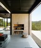 Passionate cooks, the Burtons installed a Mugnaini wood-fired oven in their kitchen and had a custom Grillery fireplace-barbecue built into the concrete block wall on their deck. Beneath the grill they store oak firewood collected from their property. Photo of Cozy Fireplaces modern home
