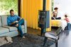 A Rais Pina wood-burning stove keeps things cozy on the West Elm Henry sofa and Eames lounge chairs. Photo of Architects Get Crafty With Budgets to Build Cost-Effective Modern Homes modern home