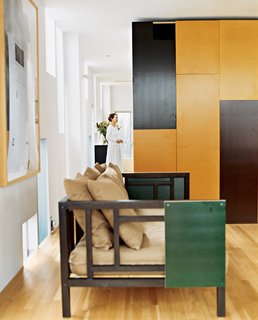 In the Venice, California, home of architect Lorcan O’Herlihy, operable panels of the built-in cabinetry, in chocolate and caramel colors, offer cues to the color palette of more mobile furnishings. Using the same panel material, the architect customized a West Elm couch for the living room. Photo by Misha Gravenor.