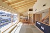 Modern home with Living Room, Bench, Wall Lighting, and Light Hardwood Floor. The 13-foot-wide sliding window provides abundant natural light year-round. The staircase was placed at the building's center to maximize openness and make space for the carport below. The blackboard is for the couple's young son, Takuma, to play with and practice writing. Photo 2 of Yanagisaki House