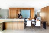 Modern home with Kitchen, Glass Tile Backsplashe, Wood Cabinet, Cooktops, Light Hardwood Floor, Undermount Sink, Refrigerator, and Wall Oven. Hawkins removed walls and swapped outdated storage for floor-to-ceiling African mahogany cabinetry. Photo of One Architect, Five Ways to Do a Modern Kitchen
