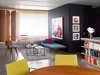 Modern home with Living Room, Chair, Bench, Coffee Tables, Shelves, and Concrete Floor. Architect Ester Bruzkus of Bruzkus Batek redesigned a compact apartment in Berlin to serve as her home. The previous layout had two bedrooms and one bathroom, but Bruzkus created an open-plan arrangement with only one bedroom to free up space. A folding wall can be pulled out for privacy. Custom furniture joins pieces by Charles and Ray Eames for Herman Miller and Gervasoni. The bathroom is enclosed within the black cube, which can be entered from either the bedroom side or the living room side. The paintings are by Berlin-based artist Niki Elbe. Photo of This Berlin Apartment Manages to Be Totally Adorable in Only 900 Square Feet