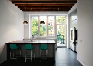 All of the Jenn-Air appliances, including the washer and dryer, are electric, as the owners asked the city to cut the gas line to the house. The kitchen cabinetry is from IKEA and features custom, matte-gray doors and Silestone countertops. The floorboards are reclaimed maple from an old tire factory, sanded and stained gray.