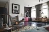 Modern home with Living Room, Pendant Lighting, Chair, Sofa, Coffee Tables, and Dark Hardwood Floor. The old wood floors throughout the open-plan space are painted a dark eggplant. The vintage PP19 armchair is by Hans J. Wegner for PP Møbler. The painting above it is by Ruben Toledo, a friend of Peter Fehrentz, the resident. A trio of Tom Dixon lights hangs over the Pirkka dining table, with bench seating by Ilmari Tapiovaara for Artek. The Berber rug is from Morocco, purchased from the Paris shop Caravane. Photo of 17 Modern Homes With Hans Wegner Furniture