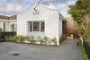 The white cement front facade was left unchanged due to heritage restrictions. From the front of the home, the new burnt ash wall at the entry is the only hint that a modern wing lies behind the unassuming exterior. Photo of Just Redo It: A Home Near Melbourne Takes Another Stab at a Dated '80s Addition modern home
