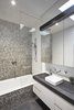 Modern home with Bath Room, Vessel Sink, Mosaic Tile Wall, and Drop In Tub. The new master bathroom features matte-black quartz countertops, a Cube sink, and a Scala wall-mount faucet. A Hansgrohe showerhead is surrounded by bold Gelsomino glass mosaic tile. Photo of Just Redo It: A Home Near Melbourne Takes Another Stab at a Dated '80s Addition