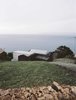 Modern home with Exterior and Concrete Siding Material. Initially unassuming, the E/C home appears hidden from the road, perched on the sloping edge of the island and partially wrapped in the basalt walls from an 18th-century farmhouse. Architects Ines Vieira da Silva and and Miguel Vieira approached the site with a vision to create a relationship with the landscape; they designed the 2,600-square-foot holiday home to not only be a simple escape, but also to frame the weathered coast and reflect its past. “Both paths to the house were designed with basalt stone, as if they were still a rural path,” Vieira da Silva says. Photo of This Modern Coastal Escape Sits Within 18th-Century Stone Walls