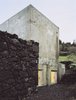 Modern home with Exterior and Concrete Siding Material. The new concrete exterior has already been transformed by the rain and humidity of the Azores, and now sports an aged look. The color contrasts with the basalt wall and dark soil of the Ilha Preta ("Black Island"). Vieira da Silva anticipates that surprising patterns and textures will develop on the outer walls over time. Photo of This Modern Coastal Escape Sits Within 18th-Century Stone Walls