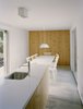 Modern home with Kitchen, Concrete Floor, and Pendant Lighting. The quiet, minimalist kitchen features a wall in the same “criptoméria" wood used for the bookshelf in the living room. A Davide Groppi Punto 2 PL light hangs over the dining table. Photo of This Modern Coastal Escape Sits Within 18th-Century Stone Walls
