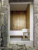 Modern home with Bedroom and Bed. Warm wooden walls ensure the simple bedroom setup, a low mattress next to a Muuto Leaf table lamp, offers more comfort than the cold stone exterior. Photo of This Modern Coastal Escape Sits Within 18th-Century Stone Walls