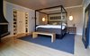 In the bedroom, Hamilton and his wife Candace reclaimed their maple wood floor from a popular bowling alley that was scheduled to be demolished. The wood was removed and used for all the bedrooms in the home. The same wood is used in furniture designed by Hamilton. He designed and built the bench located at the end of the bed. The bedroom also features wall sconces designed by George Nelson. Photo of A Couple Reclaims Bowling Alley Floors for Their Family's Bedrooms and Even Saves Some for a Custom Bench modern home