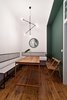 Modern home with Dining Room, Table, Chair, Pendant Lighting, Medium Hardwood Floor, and Bench. Two green accent walls—one seen here in the dining room—are the only departures from the strategically white backdrop. Wierciński and team designed the dining table and its orange steel frame, along with the seating benches and wall-mounted seat backs. A Sticks pendant light from Nowodvorski illuminates the space. Photo of Our Dorm Definitely Did Not Look Like This