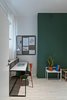 One student bedroom features the second green accent wall. Each bedroom is about 140 square feet and includes places for sleeping and studying, plus built-in IKEA wardrobes. The custom desk is paired with an orange IKEA chair. The small metal accent table and magnetic wall board are also by Wierciński. Photo of Our Dorm Definitely Did Not Look Like This modern home