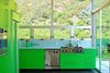 The surrounding, rolling landscape of this Malibu home influenced designer Bruce Bolander’s use of green on the cabinets and appliances in this kitchen. Photo of Tips and Tricks for Bringing Color Into the Kitchen modern home