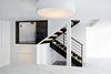 The kitchen island, illuminated by Flos Smithfield ceiling lamp, faces the steel entry stair, framed through a window. The steel was stripped and painted, and new L-shaped wood treads, steel railing, and wood handrail were subsequently fitted. Photo of Ever Dream of Taking Over Your Neighbor’s Apartment? modern home
