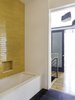 In the kids’ bath, Ann Sacks slate tile is again used on the floor, while Heath tile in a more playful Mango hue makes for a cheery wall feature. The tub is wrapped in Celador quartz, which continues up the surrounding walls. Tom Dixon Felt pendant lights hang outside the second-floor hallway. Photo of Ever Dream of Taking Over Your Neighbor’s Apartment? modern home