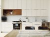 On the first floor, the kitchen features simple white IKEA cabinetry juxtaposed with a natural wood surround for the hood, also repurposed from the original fir beams. Photo of It's Back to Basics for This 1901 Brooklyn Town House modern home