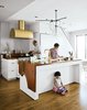 Modern home with Kitchen, Range Hood, and White Cabinet. The Mandayam–Vohra family gathers under one of Workstead’s signature three-arm chandeliers, shown here in its horizontal configuration. Photo by: Matthew Williams Photo of Material Focus: Custom Walnut Designs