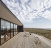 LLaumett refers to the extended patio as its own entity—a calm place to sunbathe or stare out to the ocean at any time of day. It is made of pine and covered in an opaque Osmo glaze. The chairs were constructed by the owners. Photo 2 of Unplugged modern home