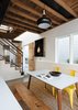 Modern home with Dining Room, Chair, Table, and Pendant Lighting. Throughout the house, Curtiss mixed natural materials with industrial ones. Downstairs, fir and cedar wood on the doors and open-joisted ceiling balance the colder, industrial feel of the concrete floor and steel staircase railing. In the dining room, a pendant lamp from RLM Lighting hangs above a table that combines Cherner table legs with a new white laminate top. The yellow chairs are by Tolix. Photo of 40+ Yellow Modern Home Design Ideas