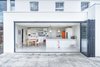 An enormous bi-fold door from Sun Paradise peels back to open the upgraded kitchen-dining area to a new raised terrace. The home's exterior is wrapped in an insulated render system. Photo of Think a Victorian Villa Can't Be Made Modern? Think Again modern home