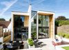 Modern home with Exterior. The cedar-and-glass structure rises over an expansive rear patio. Although it is larger than some of its neighbors, the home nearly matches the height line of the surrounding houses due to its flat, modern roof. Photo 2 of Wrap House