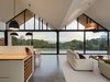Modern home with Living Room, Pendant Lighting, and Sofa. The home’s dramatic ceiling defines its interior, inviting a more understated approach to décor. Natural wool blend carpets help delineate boundaries in the open-plan space while softening the industrial appearance of the polished concrete floor in the kitchen, bathrooms, and entryway. Photo 4 of Lookout House