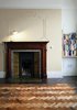 Modern home with Living Room, Medium Hardwood Floor, Table Lighting, Accent Lighting, Dark Hardwood Floor, Shelves, and Standard Layout Fireplace. British artist Maisie Broadhead elevates the nuisance of an unsightly lamp cord to over-the-mantel art with this clever bit of DIY design.—Aaron Britt Photo of Cozy Fireplaces