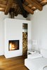 Modern home with Living Room, Medium Hardwood Floor, End Tables, Sofa, Table Lighting, and Wood Burning Fireplace. At a renovated farmhouse in the Italian countryside, a crisp, modern white plaster fireplace and hearth infuse the interior with coziness and warmth. The firewood is stacked in a nearly-frameless niche next to the fireplace that is lined with metal, adding a bit of shine that contrasts with the rustic firewood and wood ceiling and beams above. Photo of Cozy Fireplaces