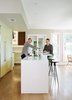 Modern home with Kitchen, White Cabinet, Undermount Sink, Wood Cabinet, Medium Hardwood Floor, and Recessed Lighting. Dan Pacek, left, and John Roynon prepare cocktails at their 12-foot “display island” in the renovated kitchen of their home in New Jersey. The couple bought handles matching those on their Thermador refrigerator and used them on a set of pantry doors, one of which conceals the steps to the basement. Photo of Airy Kitchen Additions