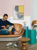 Modern home with Living Room, Sofa, End Tables, and Medium Hardwood Floor. Aumas reads on a vintage Swan sofa by Arne Jacobsen. The teal side table is from a Berlin flea market; the walnut stool by Charles and Ray Eames is from an antique store in Brussels; Aumas himself made the art on the wall. Photo of Homes Filled with Colorful Furniture