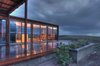Modern home with Outdoor, Side Yard, Desert, Shrubs, Wood Patio, Porch, Deck, and Decking Patio, Porch, Deck. The house rests just below the crest of a gently sloping hilltop and commands powerful views. Its transparency and small size aim to minimize its impact on the land. Photo of Petite Prefab with Stunning Views of the Texas Landscape