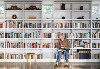 In the living area, Brothers sits on an Artek stool while perusing a selection from his library.