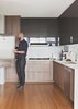 Modern home with Kitchen, Bamboo Floor, Wood Cabinet, Undermount Sink, Range, Mosaic Tile Backsplashe, and Recessed Lighting. Malboeuf stands at a Fisher & Paykel refrigerator in the kitchen. He and Bowie shopped around to find appliances that balance cost and performance: the dishwasher is Bosch, the gas cooktop is Dacor, and the oven is Fagor. Walnut veneer clads the cabinets, and the floors are bamboo. Photo of Architects Get Crafty With Budgets to Build Cost-Effective Modern Homes