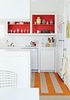 Modern home with Kitchen, Refrigerator, White Cabinet, Open Cabinet, and Dishwasher. In the kitchen, Angle removed the cabinet doors and applied a coat of Poppy Red paint by Benjamin Moore, and put down a striped linoleum floor to brighten the space. Photo of Space-Saving Hacks for Small Kitchens