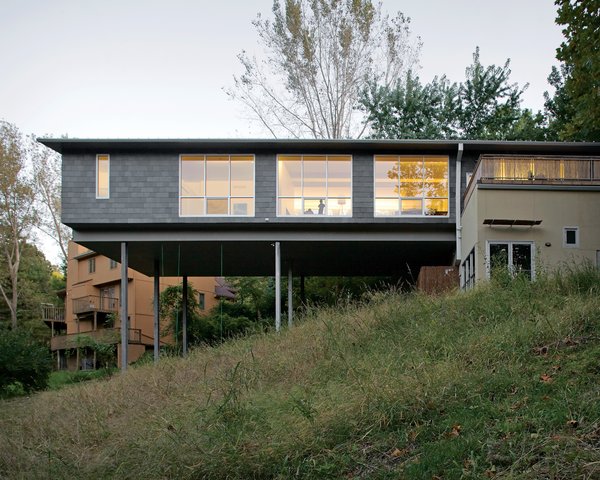 The Arnolds’ bedroom and living area float over the hillside, the large windows allowing light to flood in from both sides. A bamboo-enclosed deck sits atop the house’s foundation.
