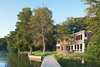 Modern home with Exterior, House, Boathouse Building Type, and Wood Siding Material. “The house’s narrow footprint works for us in terms of maximum exposure to the lake,” says Gibbs (shown here with son Blake and dog Max on the shore of Lake Iosco). Glass walls and doors by Andersen also mean that Gibbs can keep a close eye on Blake when he’s playing in the yard. A plinth of reused bedrock found on the property has become an unintended place for active play. Photo of Stunning Waterfront Structures