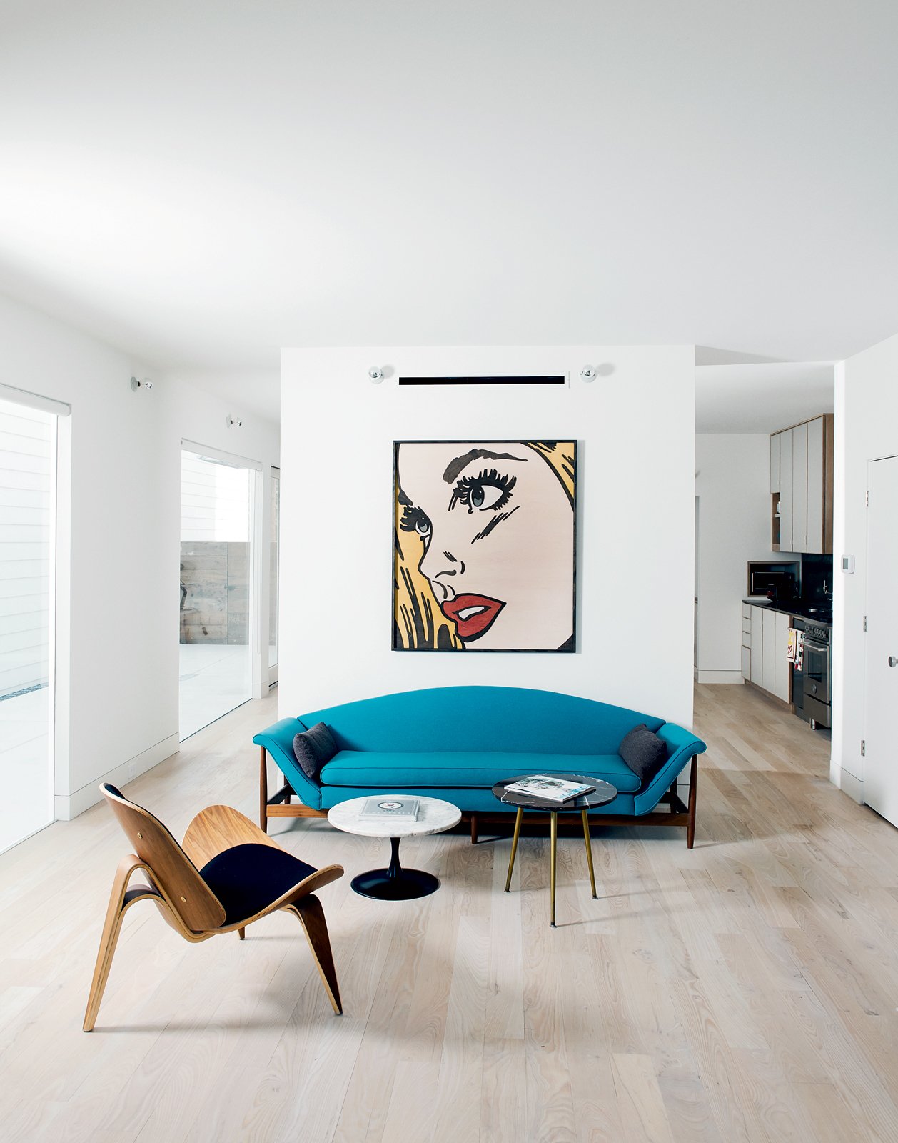 modern living room with blue curved sofa and mitch mcgee print