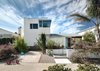 The front facade of the home shows the two-story addition seamlessly integrated with the original single-level ranch house. Patterns and details in the new structure were thoughtfully chosen to complement design elements from the original remodel. The concrete stem wall of the garage addition was laid out in a parquet pattern similar to the plywood parquet at the front entrance. The fine sand stucco finish creates visual cohesion between the two structures. Photo of An Eye-Catching San Diego Addition with a Curved, Two-Story Garage Door modern home