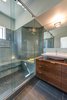 The new master bathroom also benefits from its position along the canted exterior wall. The couple initially envisioned a tub for the space, but realized during the design process that it would pose a functional challenge when paired with a push-out casement window. Bringing in valuable light and air, the casement window remained in the final design, while the tub was changed to a shower. The geometric bathroom features a custom walnut vanity by the Building Workshop, ash porcelain tile floor, and Modwalls Lush glass wall tile. Photo 6 of An Eye-Catching San Diego Addition with a Curved, Two-Story Garage Door modern home