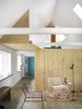 The most rigorous intervention was the internal opening-up of the house by removing two-thirds of the walls and ceilings. This creates one large living and kitchen space that extends to a lounge on the first floor. The protruding storage box (upper left) marks the transition to the library corridor and vertically frames the living room. Photo by Thomas Ibsen. Photo of Cozy Scandinavian Abodes modern home